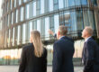 2 mannen en 1 vrouw staan voor een gebouw