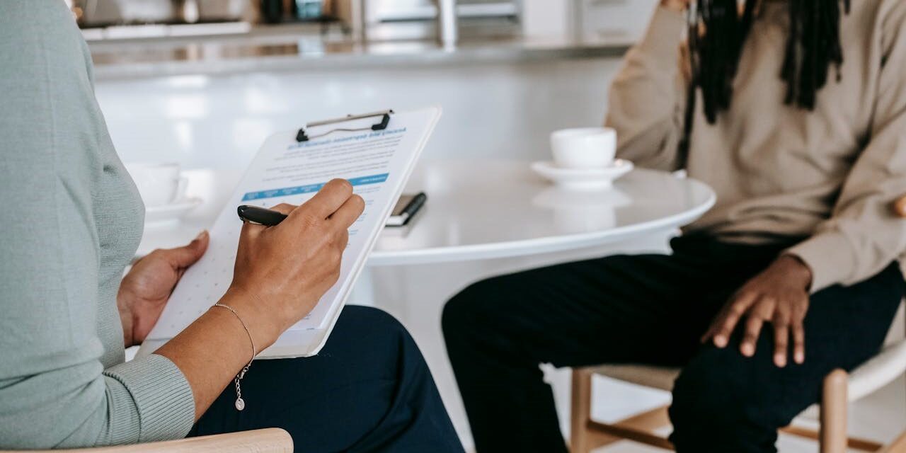 HR-medewerker voert een gesprek met een medewerker aan tafel met een evaluatieformulier in de hand