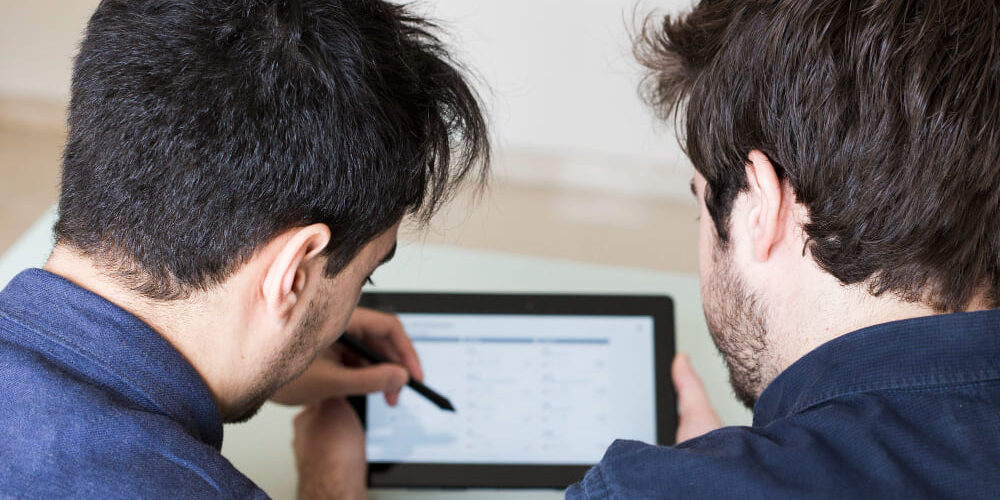 2 mannen kijken naar een tables scherm