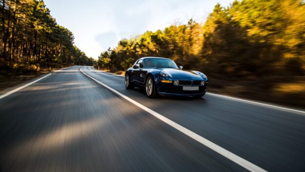 Rijdende auto met start-stopsysteem Auto rijdt op lege bosweg, ondersteund door efficiënt start-stopsysteem voor lager verbruik.
