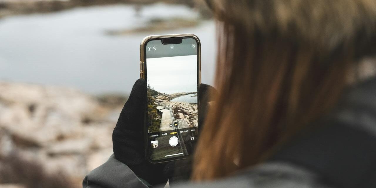 POV-foto maken met telefoon aan waterkant Persoon maakt een POV-foto van een rotsachtig landschap met water via smartphonecamera