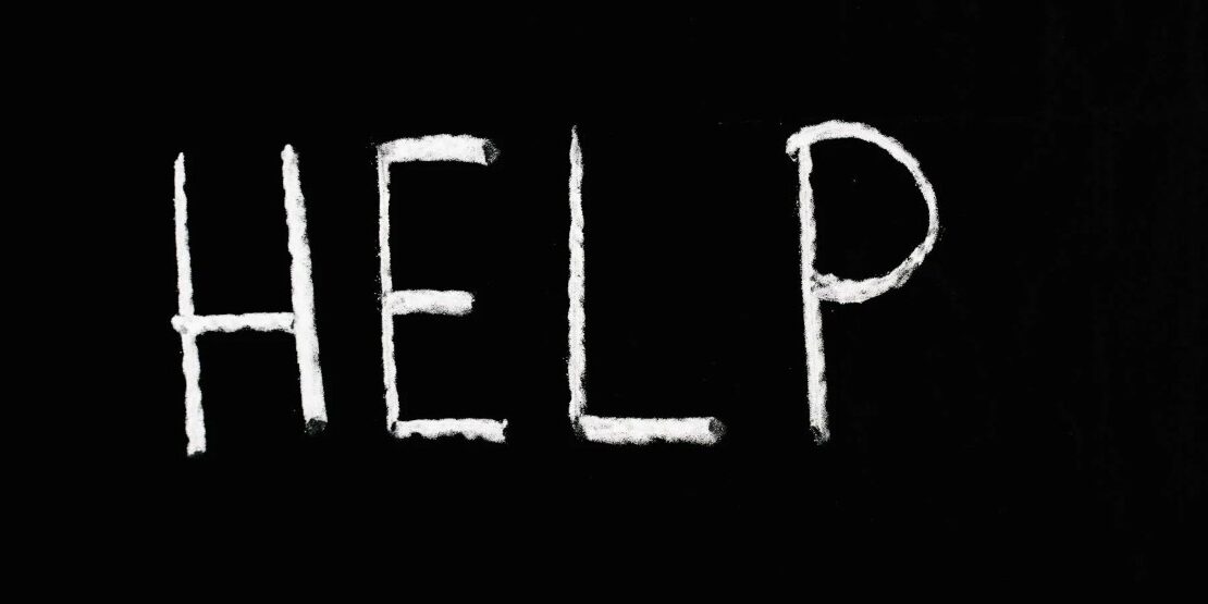 Het woord HELP geschreven in witte poederletters op een zwarte achtergrond