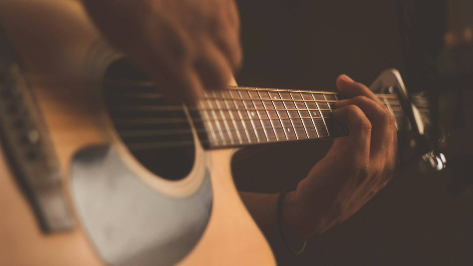 Close-up van gitaarhals met capo en vingers op de frets, voorbeeld van mensuur gitaar en fretafstand