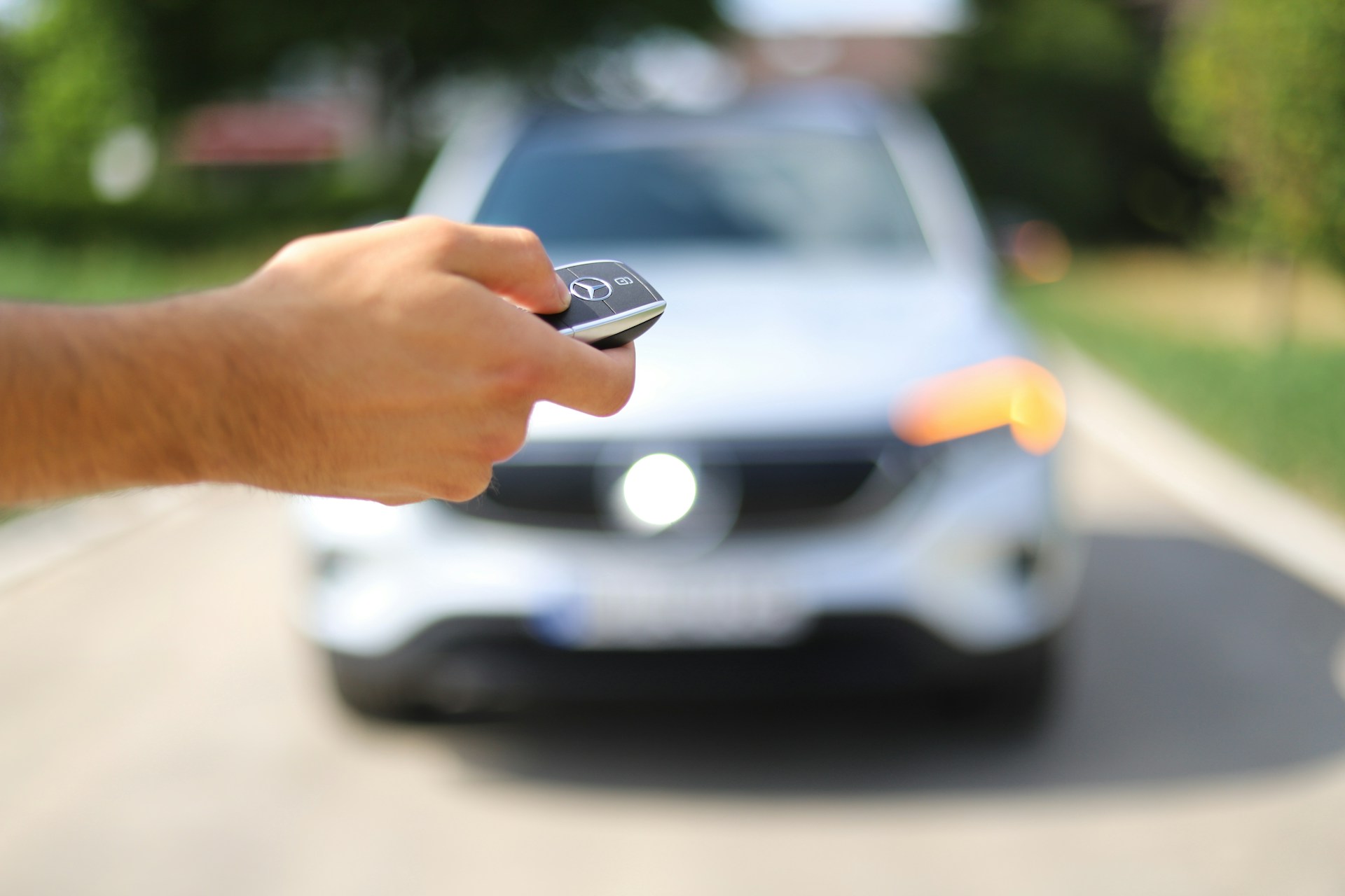 Hand met autosleutel die auto ontgrendelt via signaal, gekoppeld aan transpondercode autosleutel voor toegang en starten