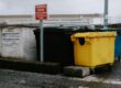 rolcontainers geel blauw en zwart langs weg