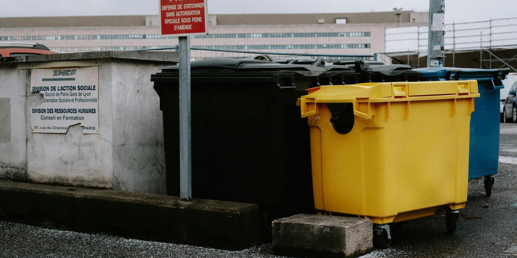 rolcontainers geel blauw en zwart langs weg