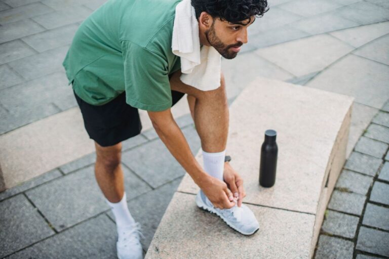 Hardloper strikt zijn schoenen voor een training waarbij stack height invloed heeft op comfort en demping
