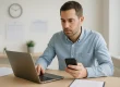 Persoon werkt aan laptop in kantoor met contractdocumenten en kalender op achtergrond, opzegtermijn abonnement.