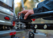 Gedetailleerde close-up van een hand die een trekhaakkoppeling op een auto plaatst, met focus op de mechanische onderdelen.