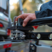 Gedetailleerde close-up van een hand die een trekhaakkoppeling op een auto plaatst, met focus op de mechanische onderdelen.