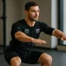 Fit persoon in zwart EMS-pak tijdens squat toont EMS training betekenis