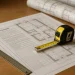 Bestek bouw blueprints met meetlint en architectuurplannen op houten bureau